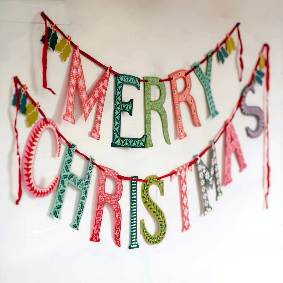 Cambridge Imprint Merry Christmas paper banner with red and green patterned letters and holly sprigs, view 3